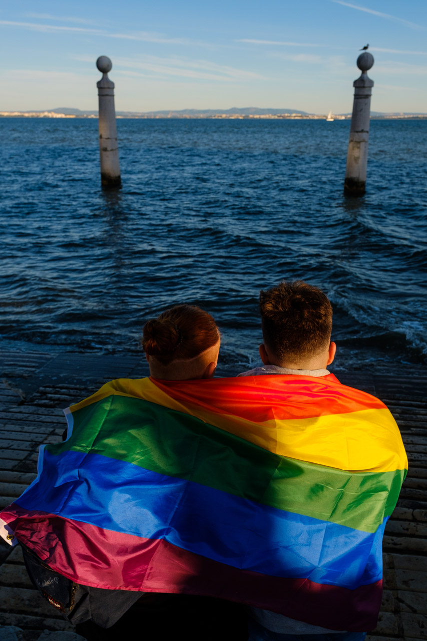 A couple seats near Cais das Colunas by river Tagus after participating in Pride parade