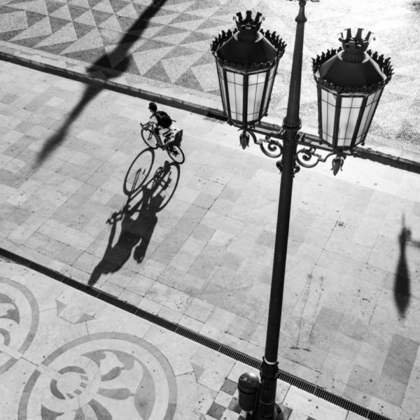 A biker carrying a child cycle through the Town Hall Square in Lisbon.