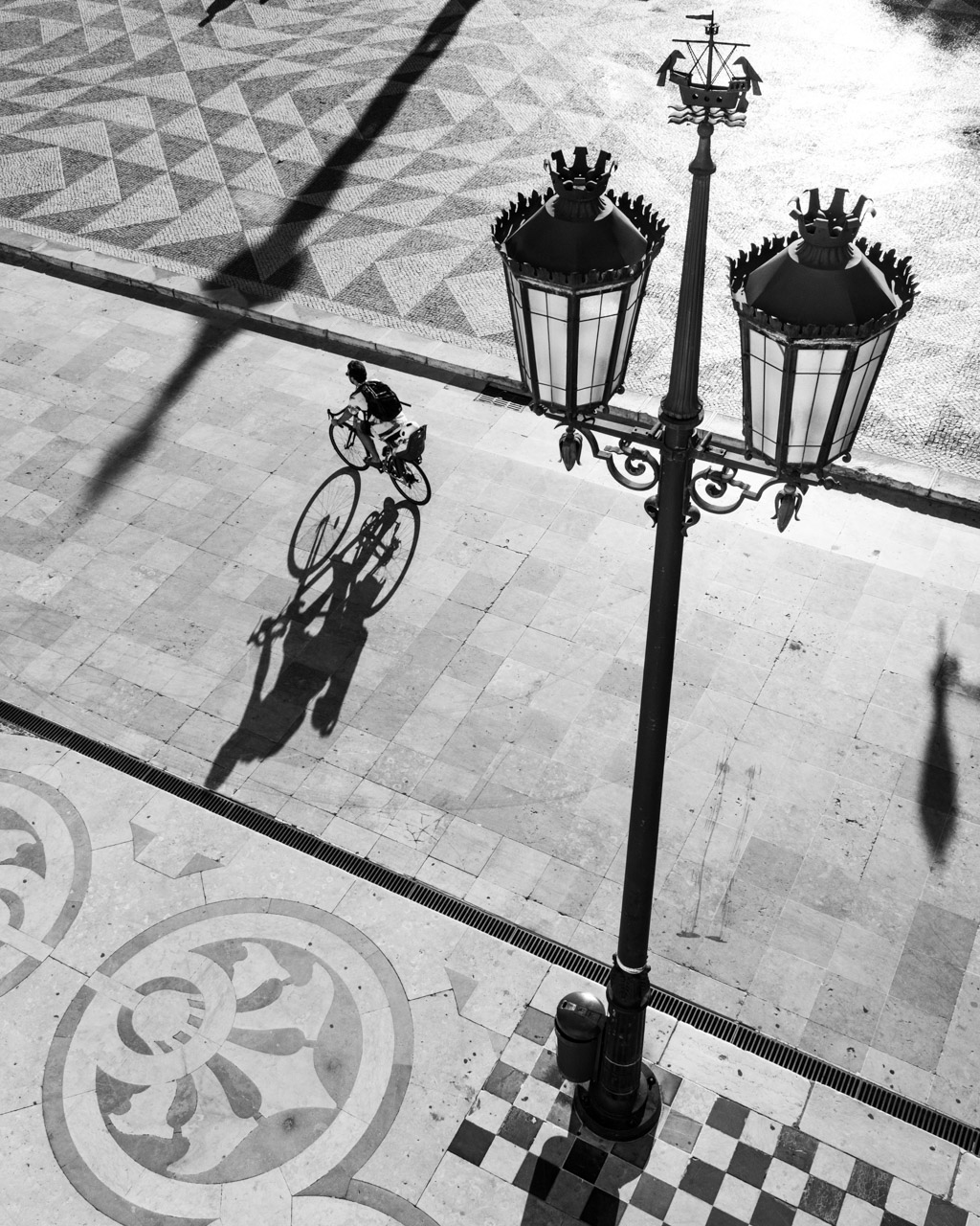 A biker carrying a child cycle through the Town Hall Square in Lisbon.